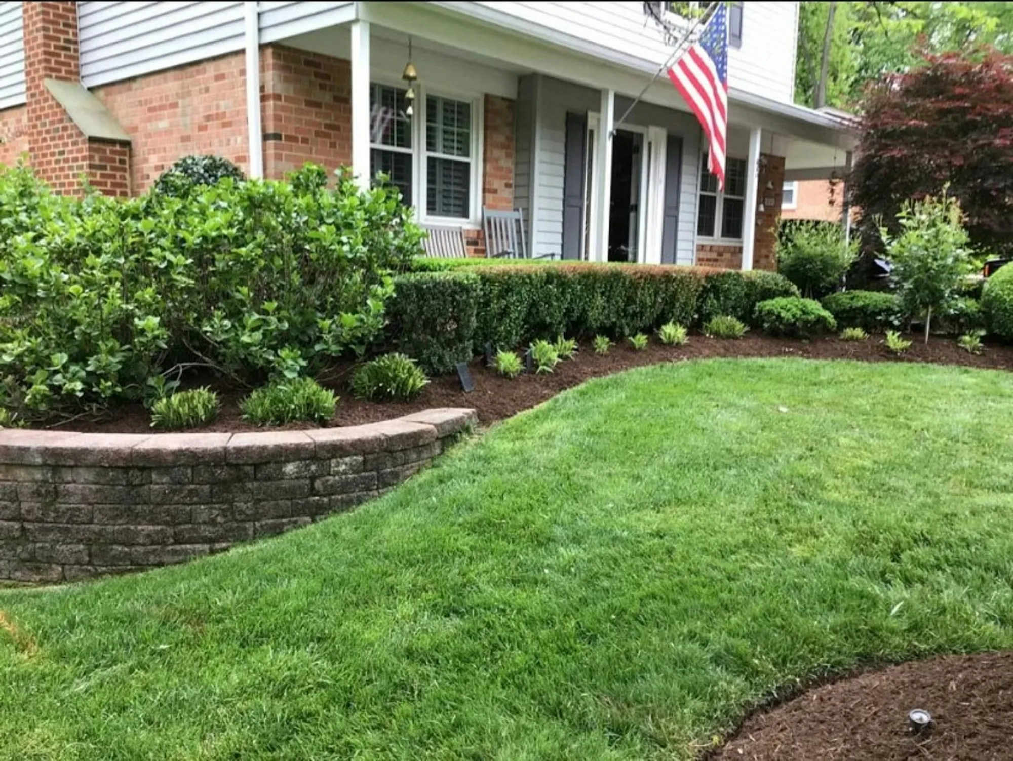 Landscaped front yard with a curved retaining wall and green lawn